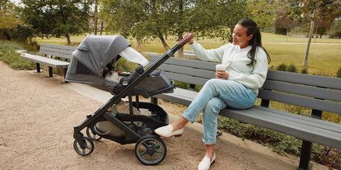 Madre con un carrito UPPAbaby Cruz V3 durante un paseo por un parque urbano